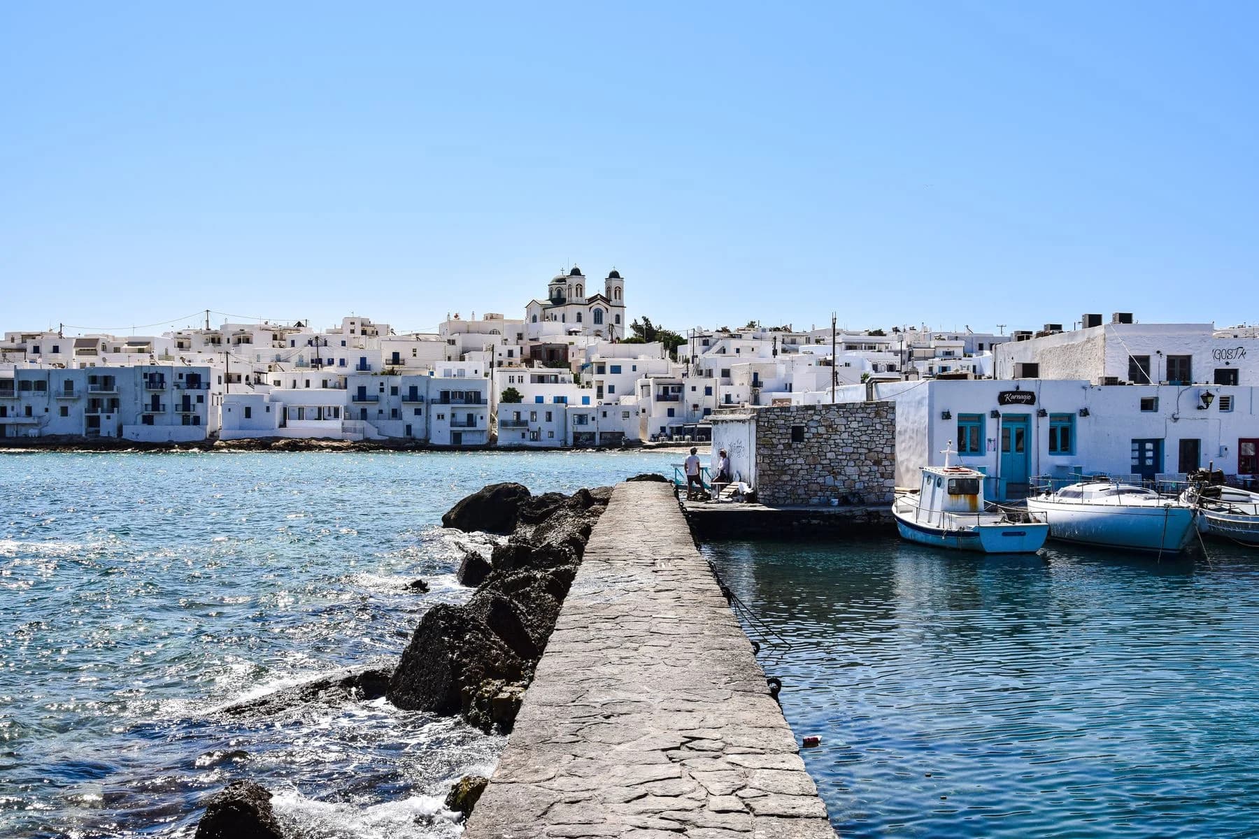 Weiße Häuser am Wasser, ein Steinpier und Fischerboote in Naoussa auf Paros